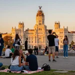 Vista de Madrid al atardecer con personas disfrutando y tomando Noticias de Madrid en un mirador popular.
